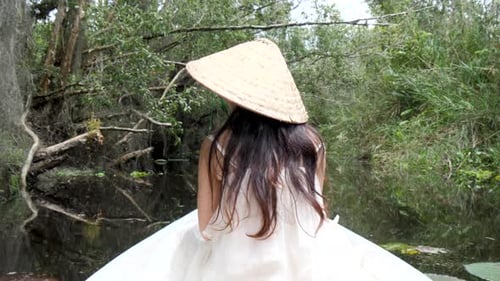Back View Of Woman In Conical Hat Riding Boat On River In Mekong Delta, Vietnam. medium shot