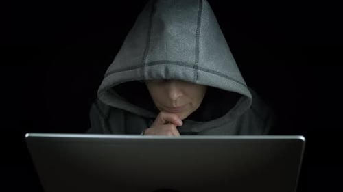 Person in Hood Using Laptop in Dark