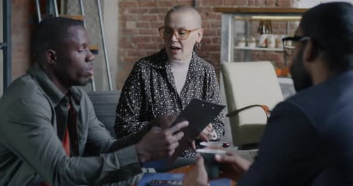 Multiracial Group of Businesspeople Talking Discussing Idea and Drinking Coffee in Creative Cafe