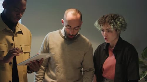 Trois collègues regardant une tablette et parlant de stratégie commerciale