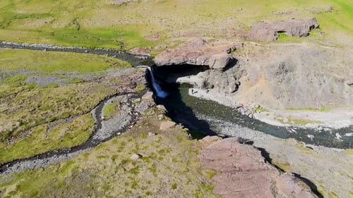 Aerial view of river and waterfall in rugged landscape, Iceland.