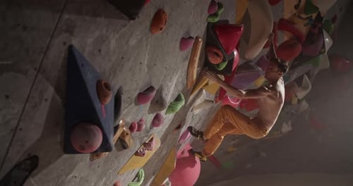 Male Rock Climber Training at Climbing Wall in Gym