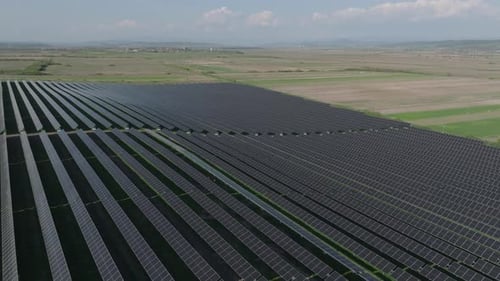 Aerial shot of vast solar panel field generating renewable energy over rural land