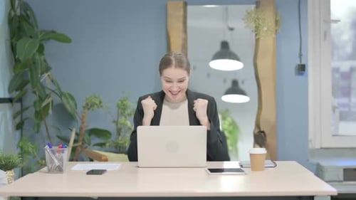 Businesswoman Celebrating Online Success on Laptop in Office