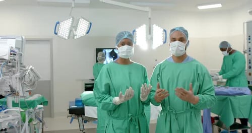 Portrait of diverse surgeons wearing surgical gowns in operating theatre, slow motion