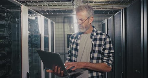 Man Working on Laptop in Server Room