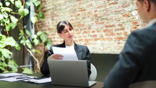 Businesswoman Discusses Documents with Businessman in Office
