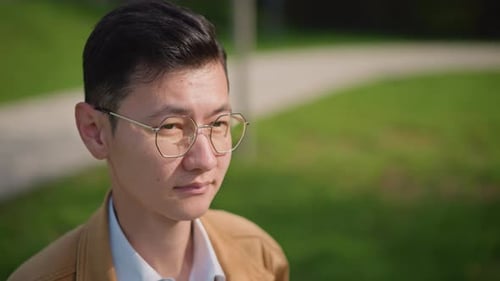 Man Sketches Outdoors Asian Man Observes City Park Contemplative Male Artist in Urban Park Setting