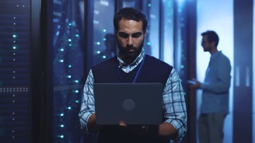 Technician working with laptop in data center