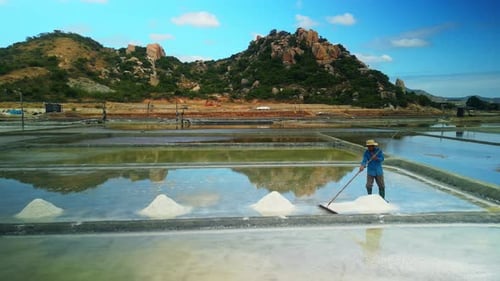 Salt Harvesting in Solar Evaporation Ponds with Mountains in Background Vietnam