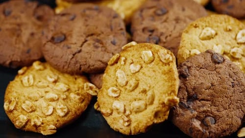 Placa plana de primer plano sobre fondo negro y azul con galletas colocadas caóticamente sobre la mesa