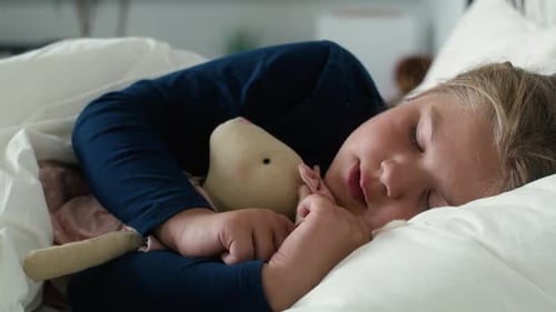 Child Sleeping Peacefully with Stuffed Animal in Bed