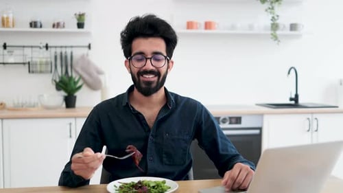 Young Adult Eats Salad in a Kitchen