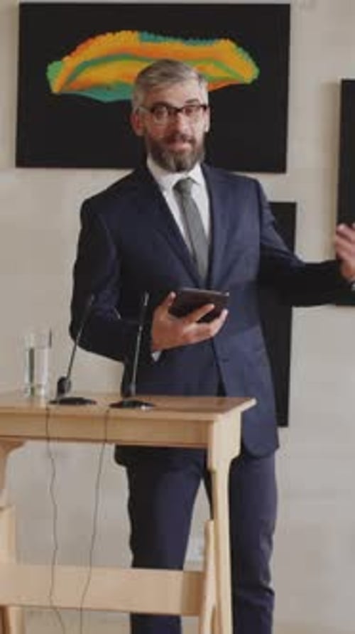 Middle-aged Man Presenting Artworks Conducting Auction in Gallery