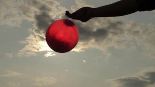 Hand Holding a Red Balloon in Golden Light