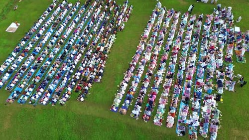 Drone shot of Muslim congregation praying Eid prayer outdoors,
