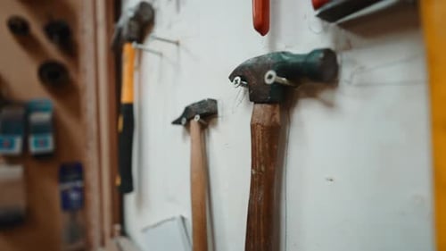 Collection of Various Hammers and Tools Hanging in a Carpenter's Workshop