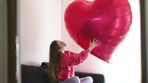 Smiling Woman Holding a Large Red Heart Balloon