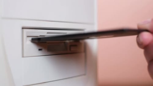 Eine weibliche Hand legt eine Diskette in die Systemeinheit ein