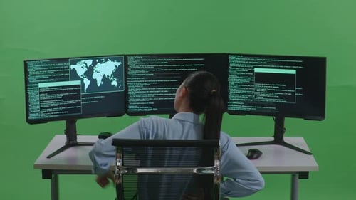 Rückansicht einer Frau mit Rückenschmerzen beim Schreiben von Code mit mehreren Bildschirmen auf grünem Bildschirm