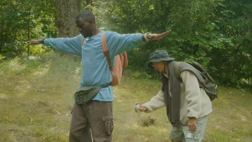 Hikers Using Insect Repellent Spray in Woods