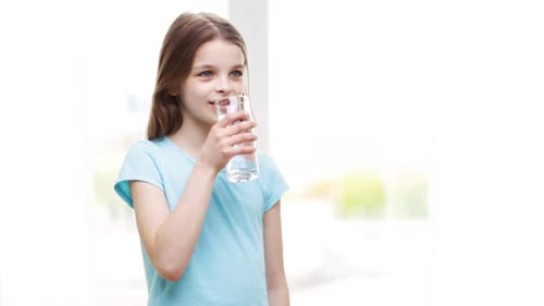Girl in Blue Shirt Drinks Glass of Water