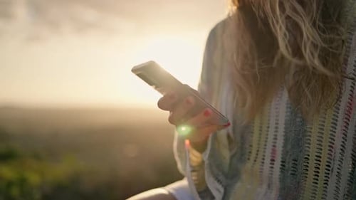 Close up of blonde young woman using smartphone in slow motion at sunset