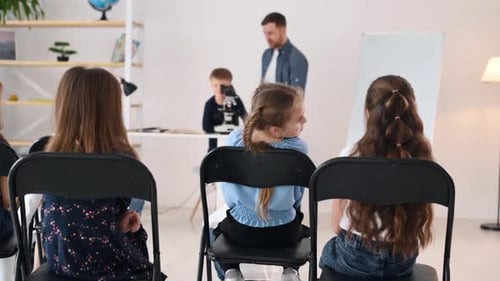 Boy looking into microscope. Group of children students in class at school with teacher