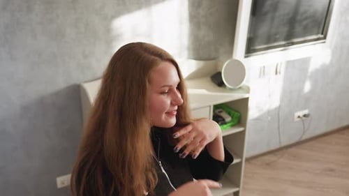 Woman Adjusts Hair Indoors in Natural Sunlight