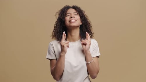 Woman with Fingers Crossed Hopeful on Neutral Background