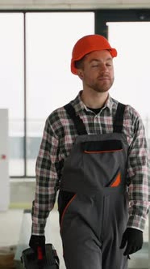 Construction Worker Walking with Toolbox in Unfinished Building