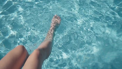 Fußbewegung im Pool mit klarem türkisfarbenem Wasser beim Entspannen im Hotel