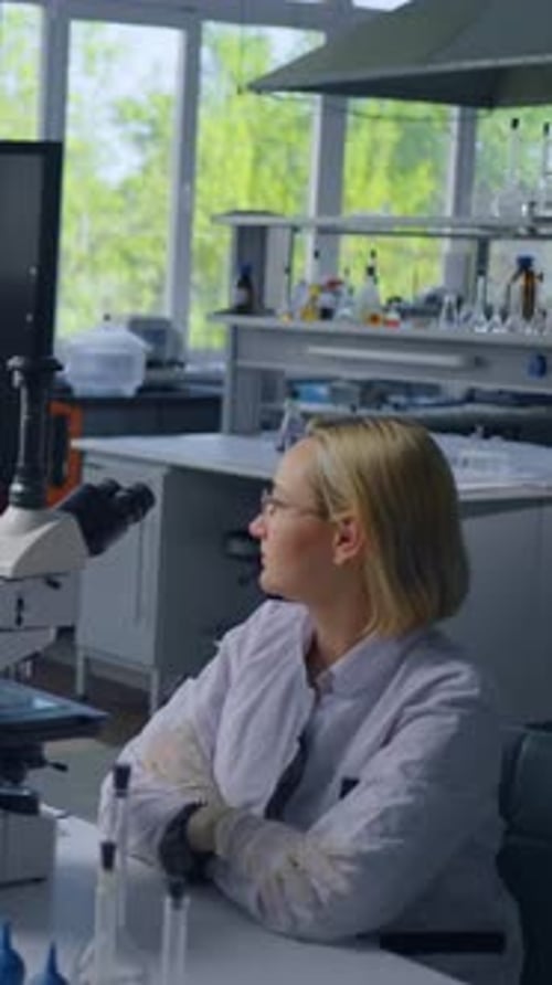 Woman Scientist in Lab Looking at Microscope Screen