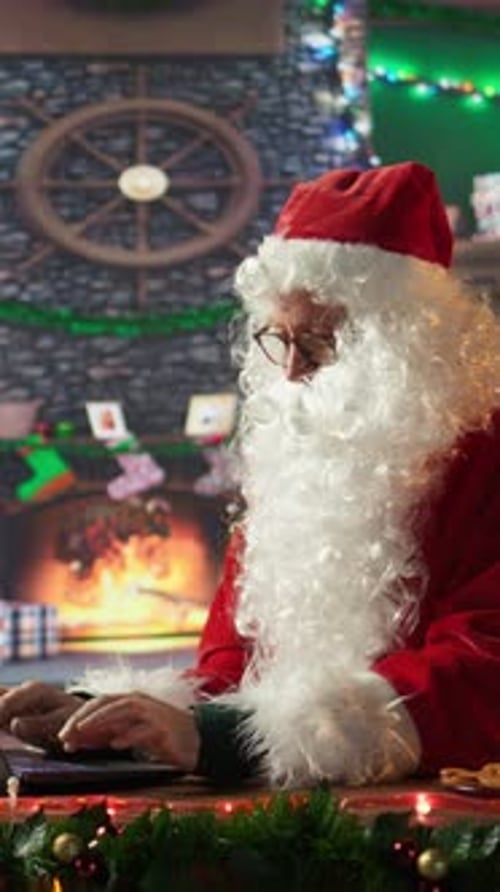 Vertical Video Santa Claus in His Red Suit Browses Webpages in His North Pole Workshop