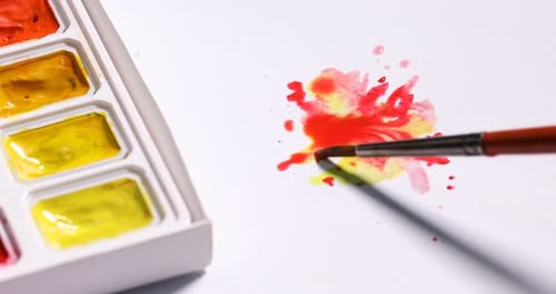 Watercolor paint splatters with brush on white paper