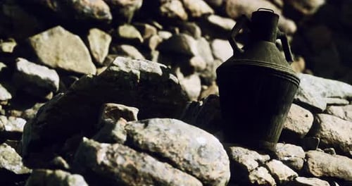 Antique Jug Resting on Rocky Ground in a Natural Setting at Dusk