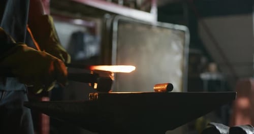 Blacksmith Shaping Hot Metal with Hammer in Workshop