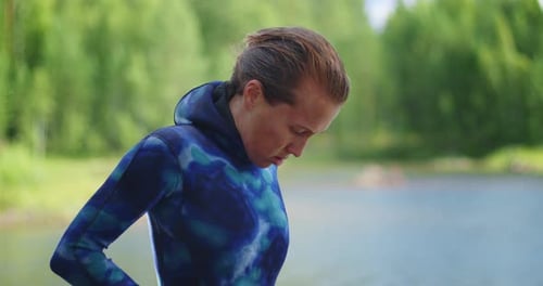 Une jeune femme enfile une combinaison bleue sur le lac