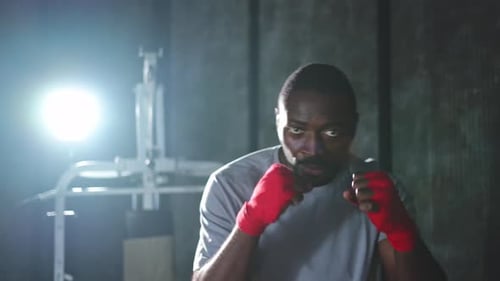 Workout in Gym African Man Fighter Ready for Fight Punching with Boxing Wraps Protective Bandages to