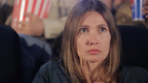 Woman Experiences Suspense While Watching a Thriller in the Cinema