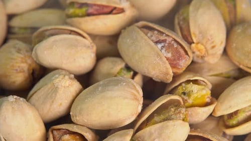Hot roasted pistachios rotate with smoke. Salted pistachio nuts for beer background close up.