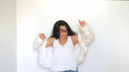 Com os braços levantados e um sorriso radiante, uma mulher gosta de uma dança despreocupada, seu traje casual e chique