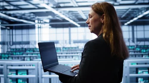 Smiling IT Expert Uses Notebook in Data Center Workspace