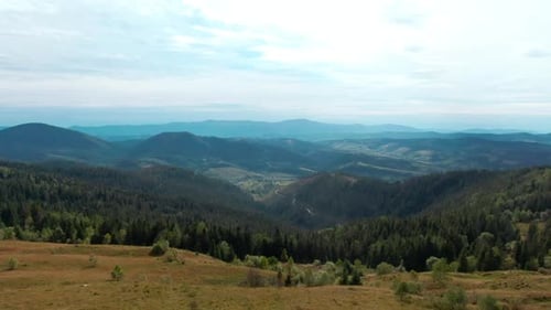 White Cloudy Sky Over Blue Mountains and Green Forest on Hills Wide Shot Picturesque Landscape in