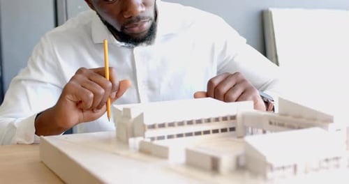 Architect working on building model, carefully measuring and designing structure