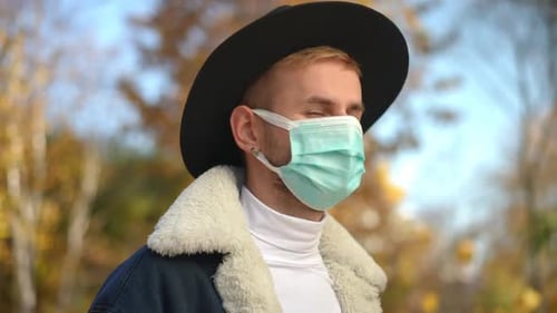 Side View Young Man in Covid19 Face Mask Standing in Autumn Park Forest Turning Looking at Camera