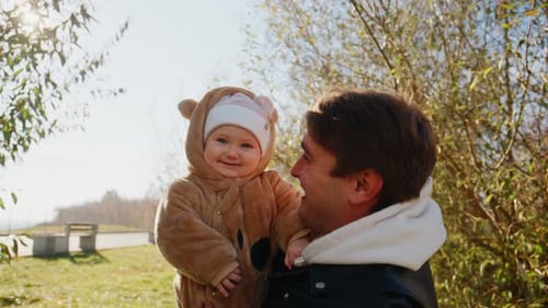 Smiling Infant with Man in Sunny Park Setting