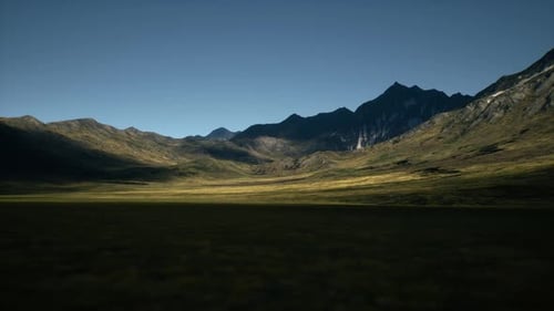 Expansive Valley Surrounded By Majestic Mountains Under Clear Blue Sky