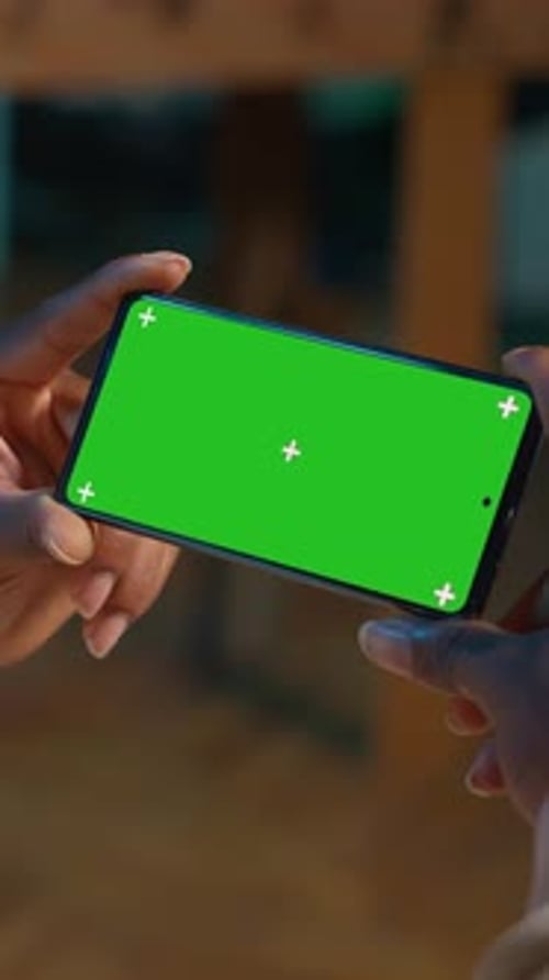 Vertical Video African American Young Adult Looks at Green Screen on a Gadget