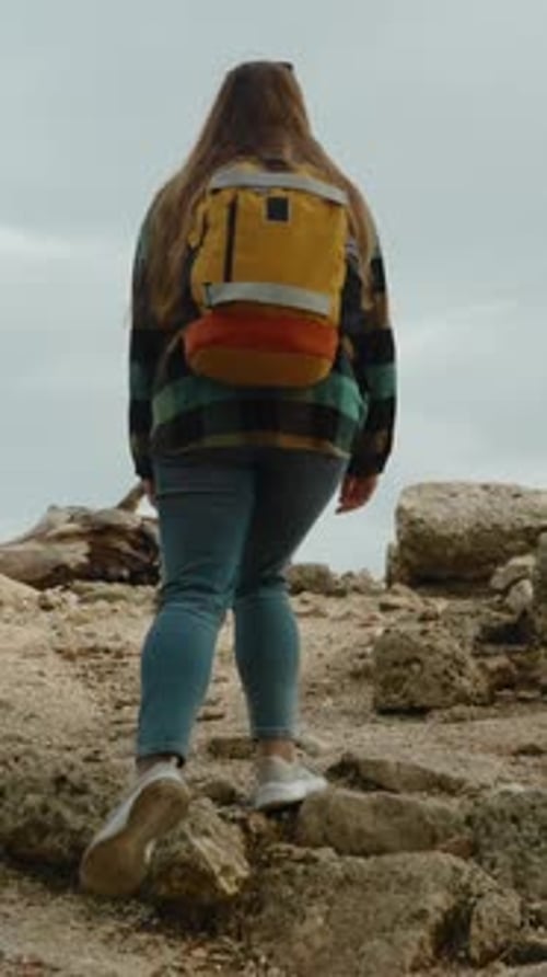 Woman Hiking on Rocky Hillside with Backpack